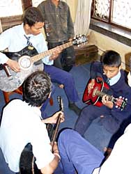 Drei Zehntklässler spielen Gitarre.