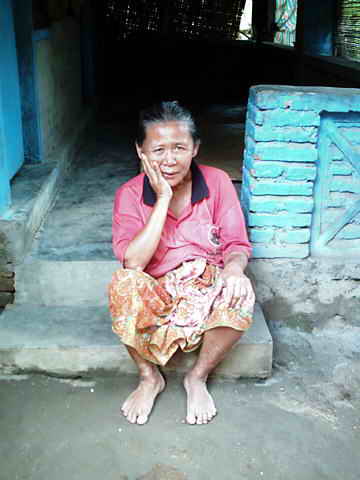 Ältere Frau auf den Stufen ihres Hauses.