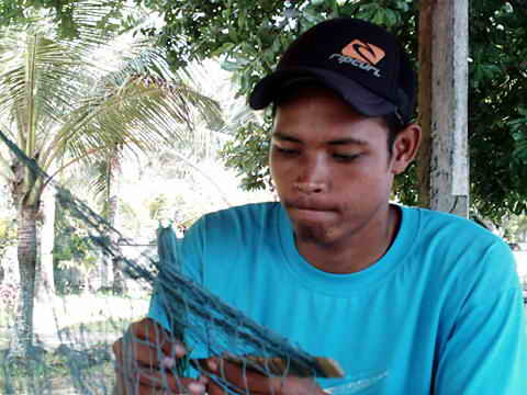 Junger Fischer repariert seine Netze.