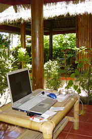 Mein Computer auf einem Bambustisch vor dem Zimmer im Garten