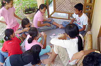 Viele Mädchen und ein Junge beim Kartenspiel.