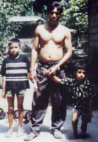 Kadek mit Vater und Bruder vor ihrem Haus.